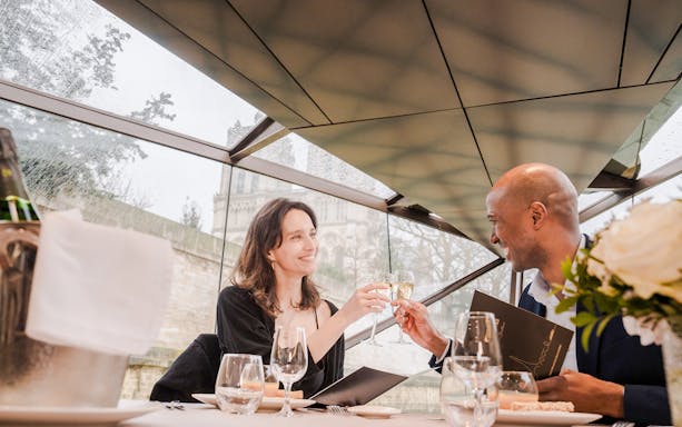 Couple toasting with champagne on a Seine River lunch cruise in Paris.