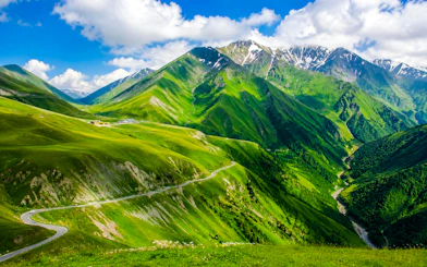 Mount Kazbek view with winding road through lush green hills.