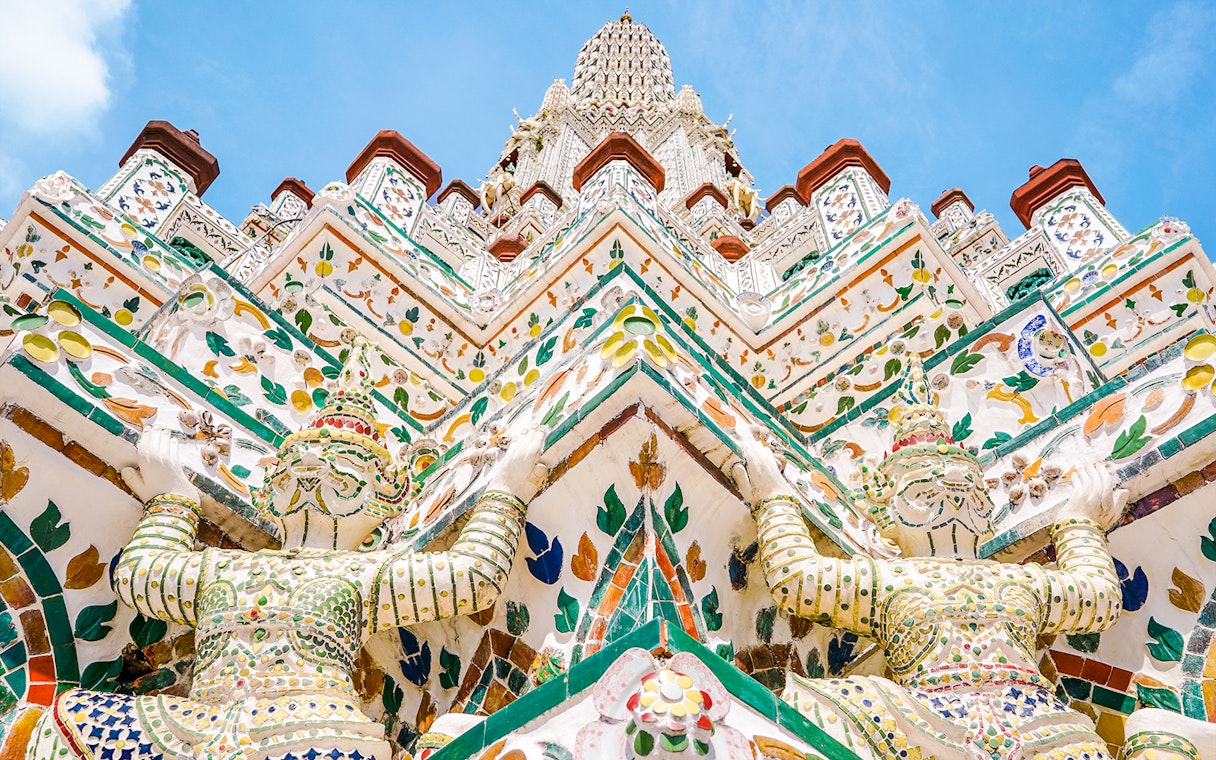Wat Arun temple intricate facade with colorful guardian statues, Bangkok.