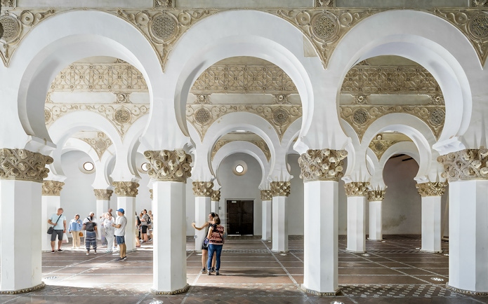Visitors exploring the arches inside Synagogue of Santa María la Blanca, Toledo.