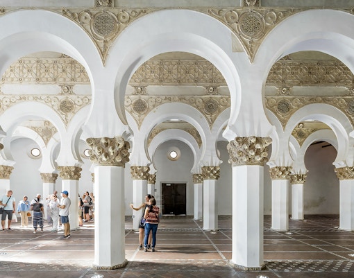 Visitors exploring the interior of the Synagogue of Santa María la Blanca in Toledo, Spain.
