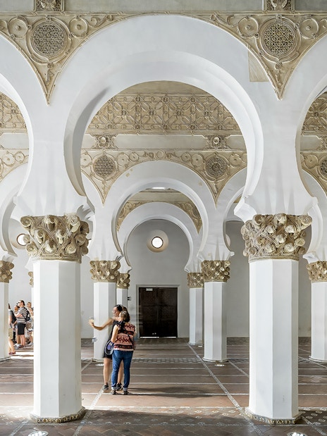 Visitors exploring the arches inside Synagogue of Santa María la Blanca, Toledo.