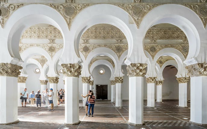 Visitors exploring the arches inside Synagogue of Santa María la Blanca, Toledo.
