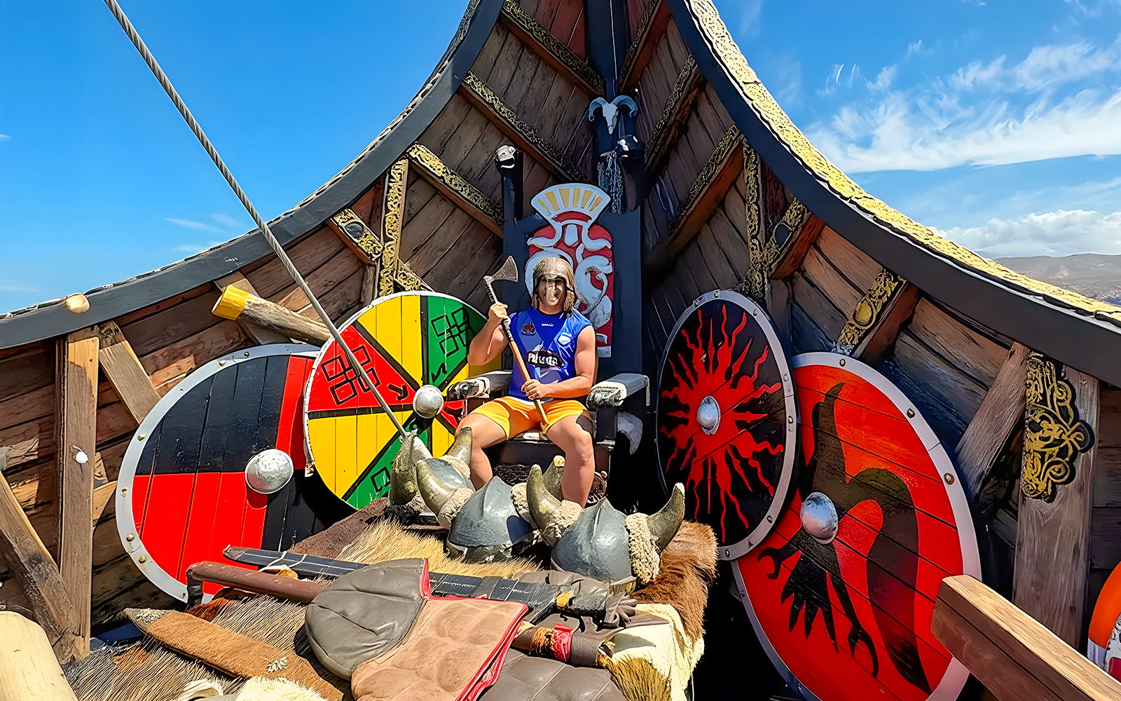 Tourist in Viking attire on a Viking cruise boat with shields and axe.