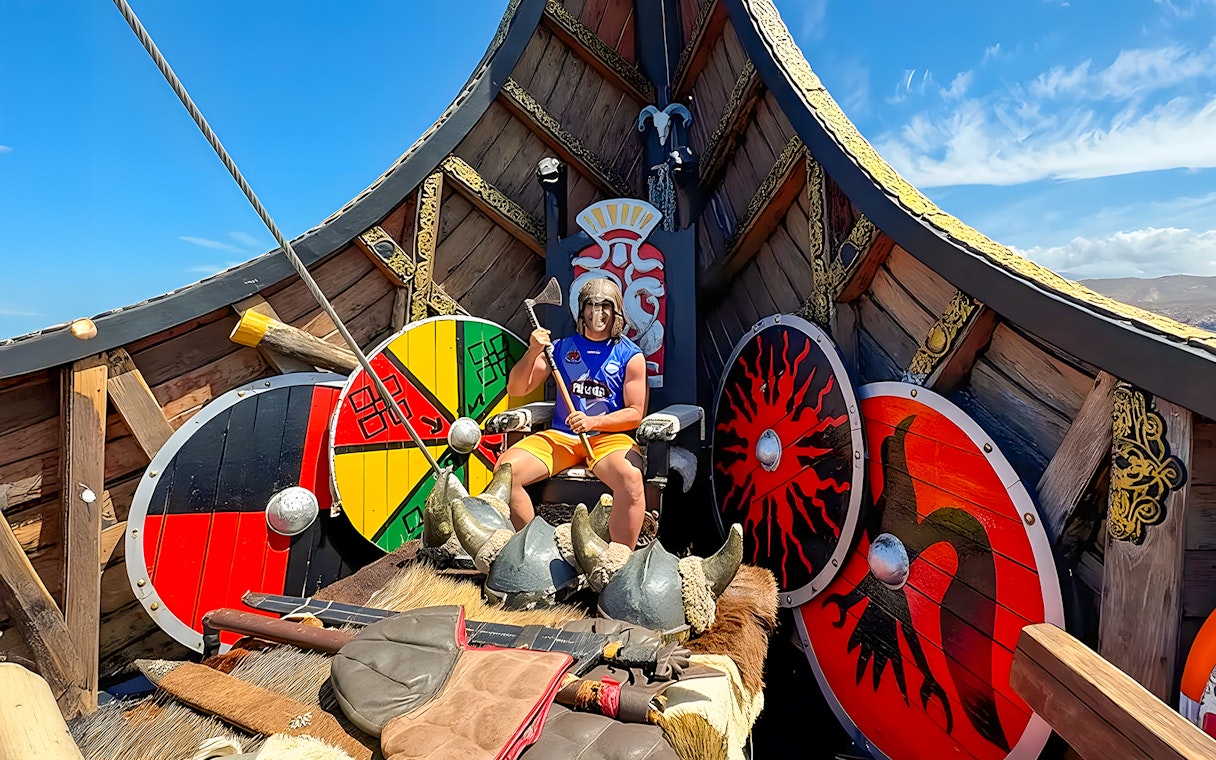 Tourist in Viking attire on a Viking cruise boat with shields and axe.