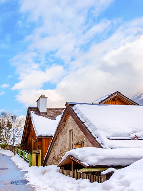Snow-covered wooden houses in Hallstatt village during winter.