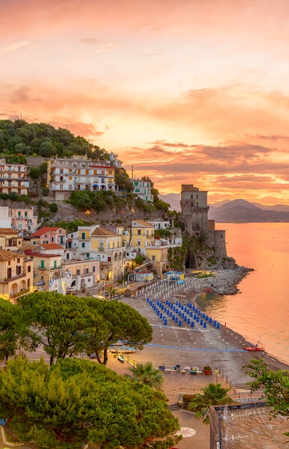 Amalfi Coast beach and colorful hillside buildings at sunset, Italy.