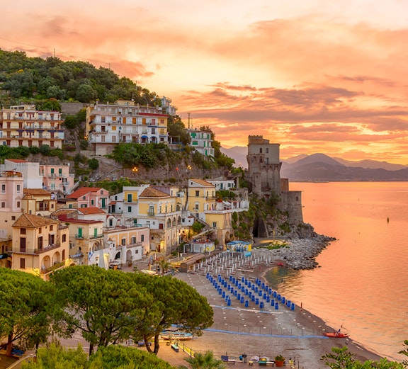 Amalfi Coast beach and colorful hillside buildings at sunset, Italy.