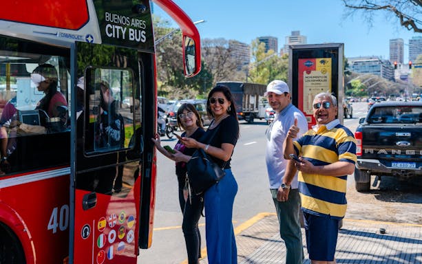 Tourists boarding Buenos Aires Hop-on Hop-off Bus on a sunny street.