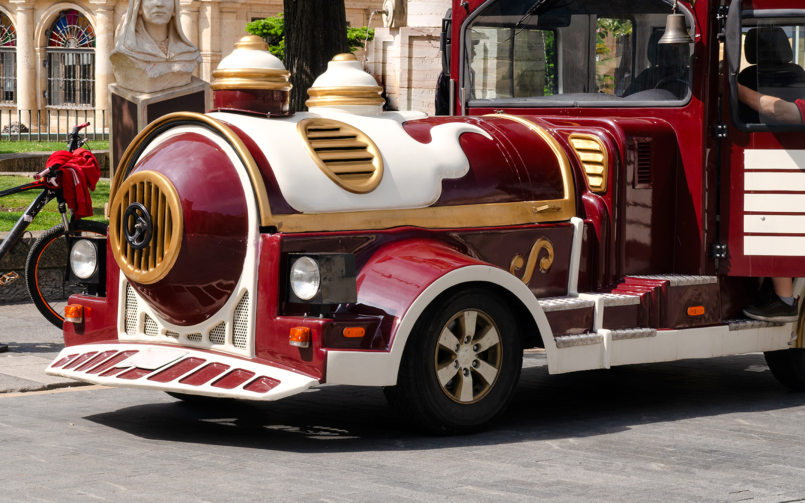 Happy Train tour vehicle in Athens, Greece, parked near a historical statue.