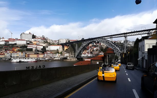 Porto GoCar tour passing by Dom Luís I Bridge and colorful riverside buildings.