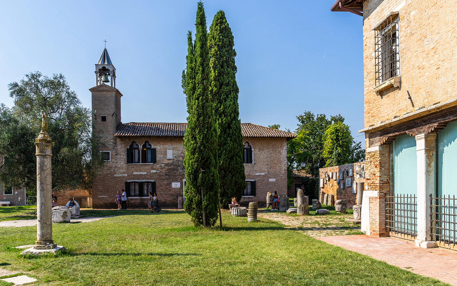 Torcello Museum courtyard with bell tower and ancient artifacts, Venice, Italy.