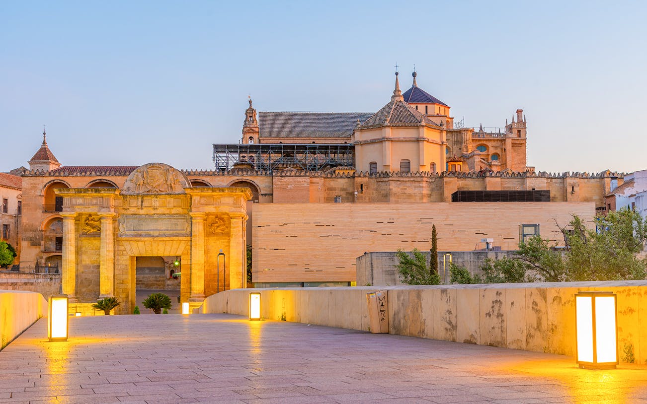 Mezquita de Córdoba exterior view at sunset with illuminated pathway.