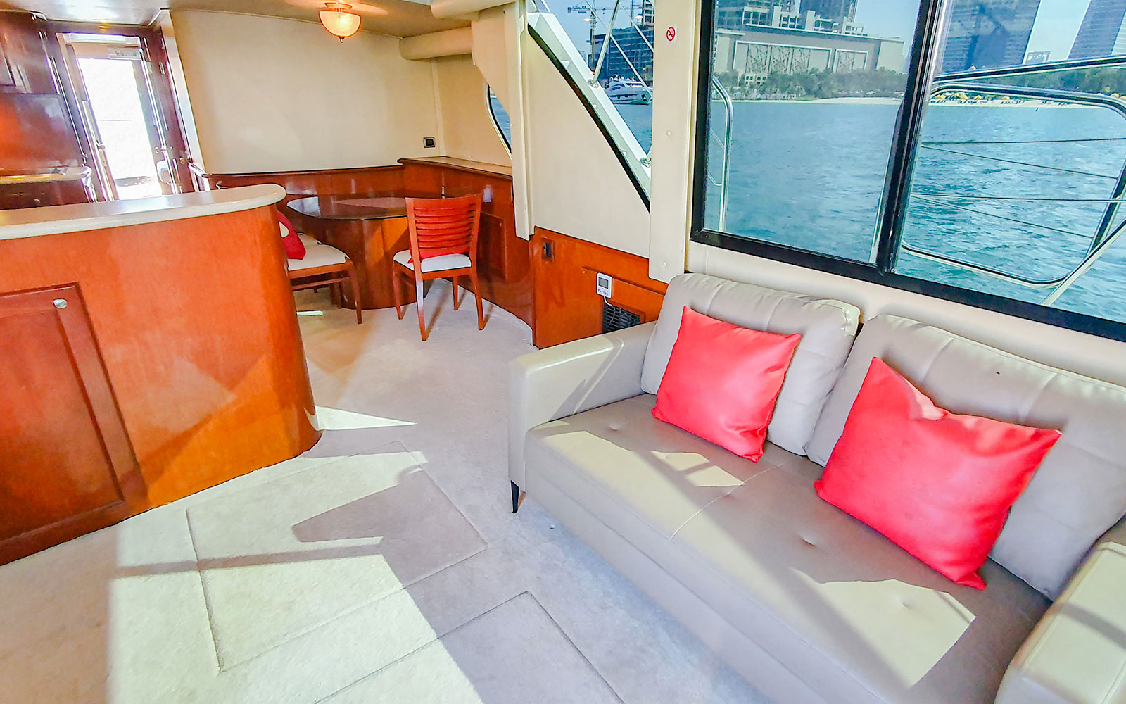 Interior of luxury yacht with seating area and view of Dubai skyline through window.