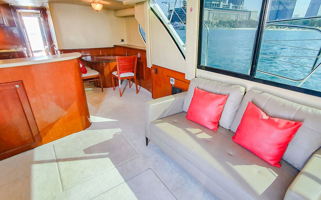 Interior of luxury yacht with seating area and view of Dubai skyline through window.