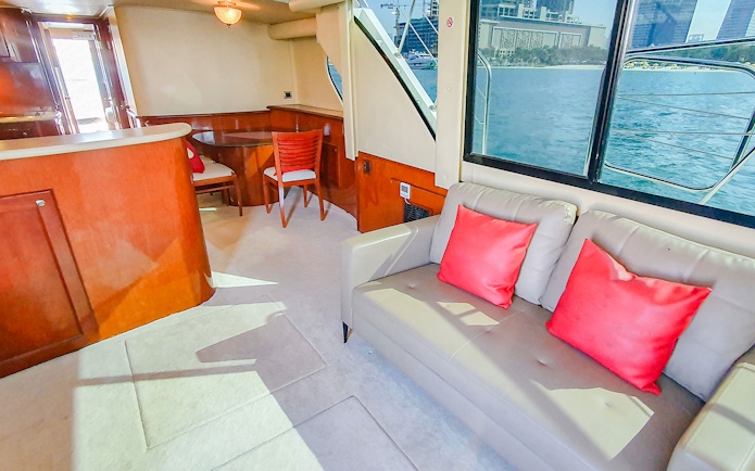 Interior of luxury yacht with seating area and view of Dubai skyline through window.