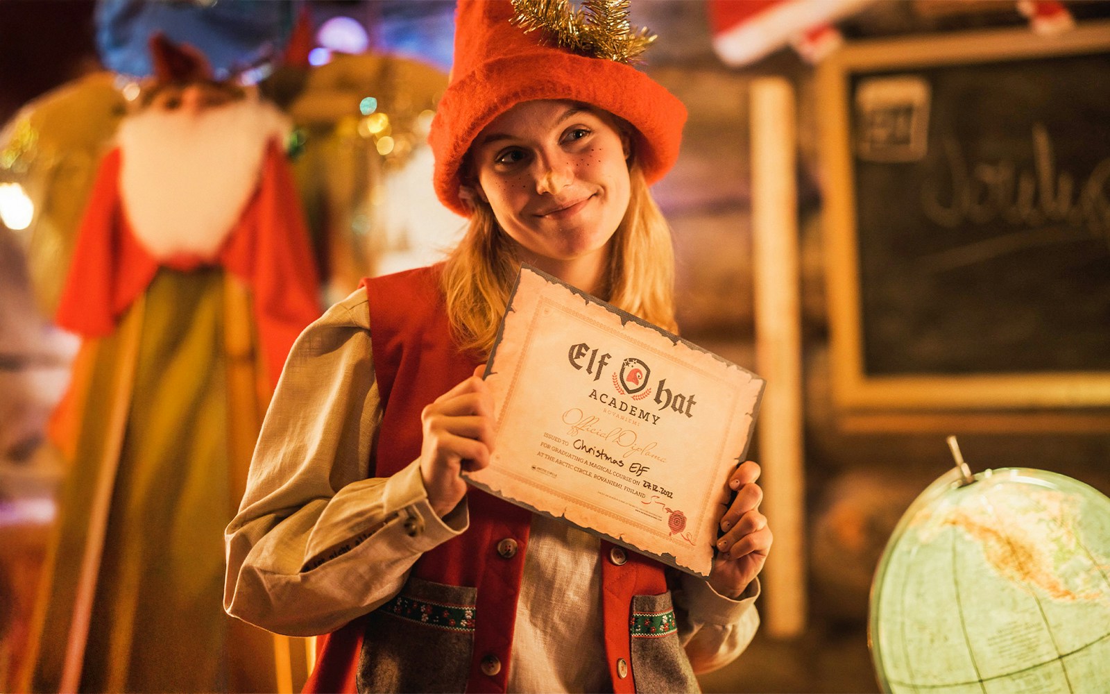 Elf Hat Academy graduate holding certificate at Santa's Village, Rovaniemi, Finland.