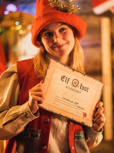 Elf Hat Academy graduate holding certificate at Santa's Village, Rovaniemi, Finland.