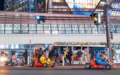Nighttime go-karting on city streets with illuminated buildings in the background.