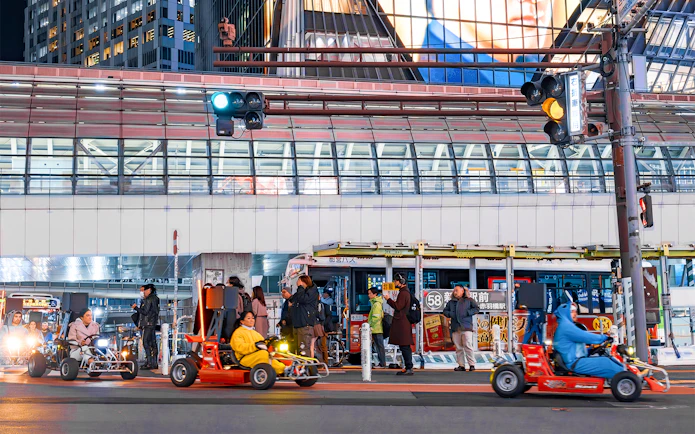Nighttime go-karting on city streets with illuminated buildings in the background.