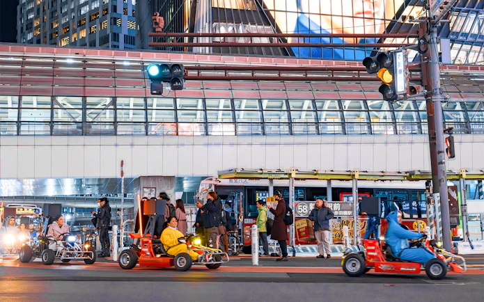 Nighttime go-karting on city streets with illuminated buildings in the background.