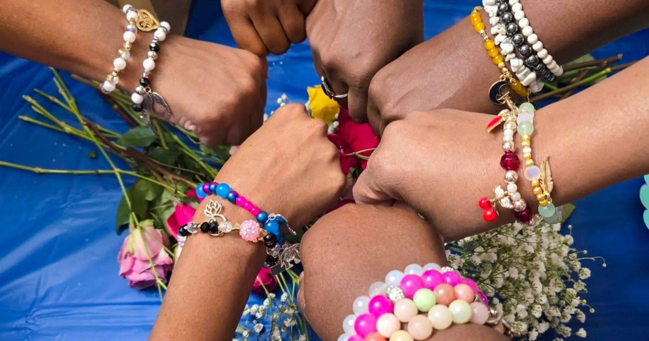 Hands wearing colorful handmade bracelets at a jewellery workshop in Essaouira.