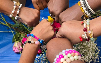 Hands wearing colorful handmade bracelets at a jewellery workshop in Essaouira.