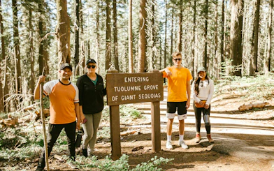 Group at Tuolumne Grove entrance sign in Mariposa Grove Redwoods.