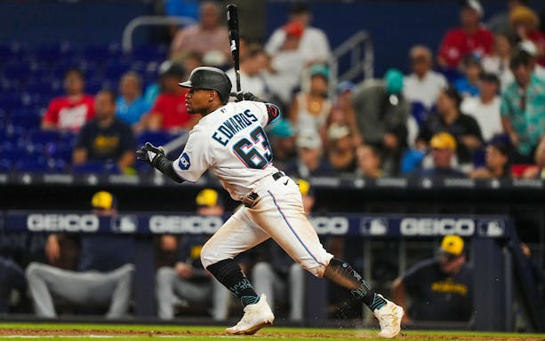 Baseball player in Miami Marlins uniform swinging bat during a game.