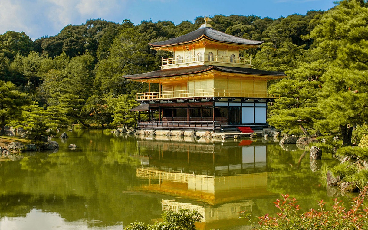 Kinkakuji Temple reflecting in a serene pond surrounded by lush greenery in Kyoto.