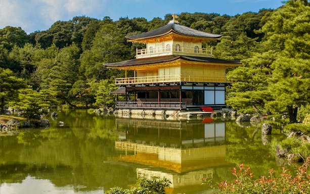 Kinkakuji Temple reflecting in a serene pond surrounded by lush greenery in Kyoto.