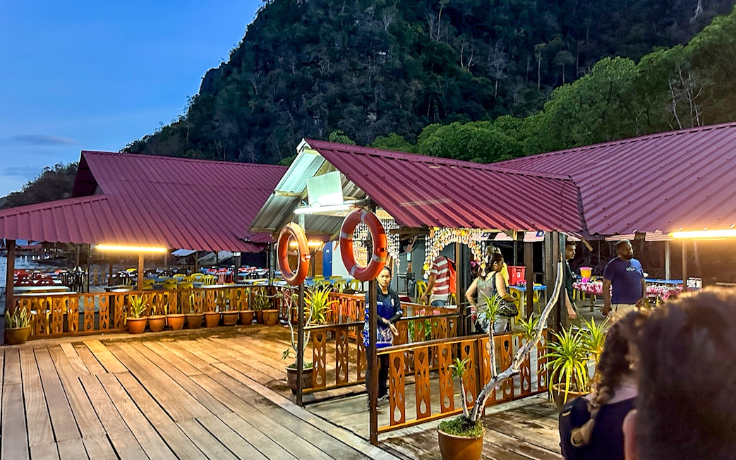 Floating restaurant platform illuminated at dusk during Langkawi night mangrove tour.