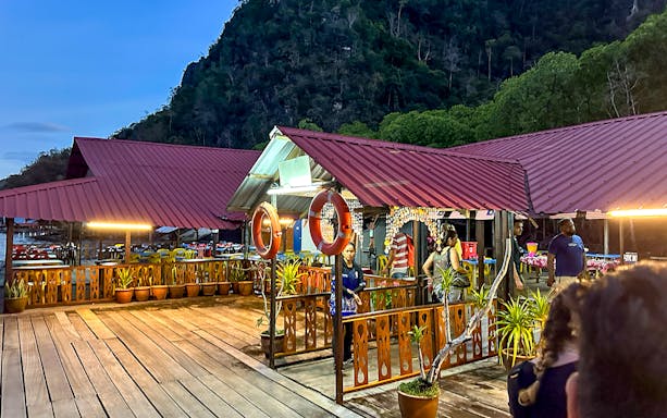 Floating restaurant platform illuminated at dusk during Langkawi night mangrove tour.