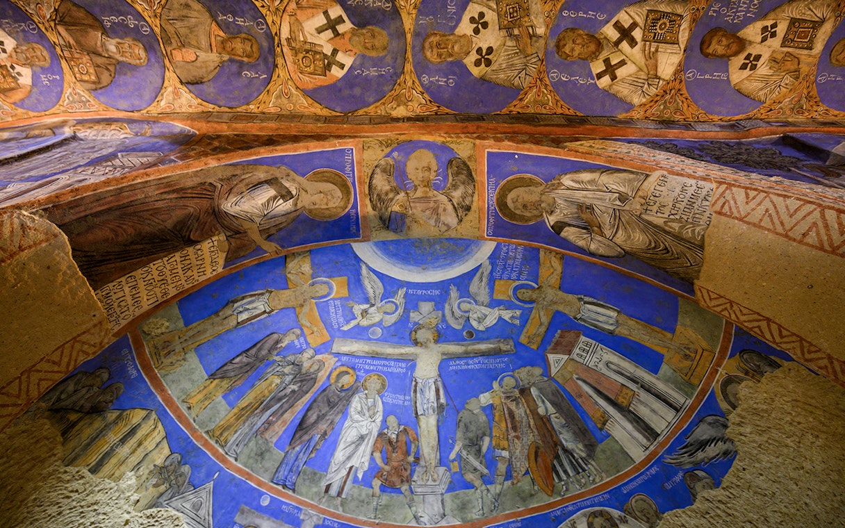 Frescos and murals depicting religious figures in ancient cave at Gerome Open Air Museum.