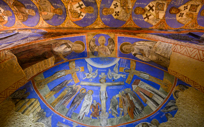 Frescos and murals depicting religious figures in ancient cave at Gerome Open Air Museum.