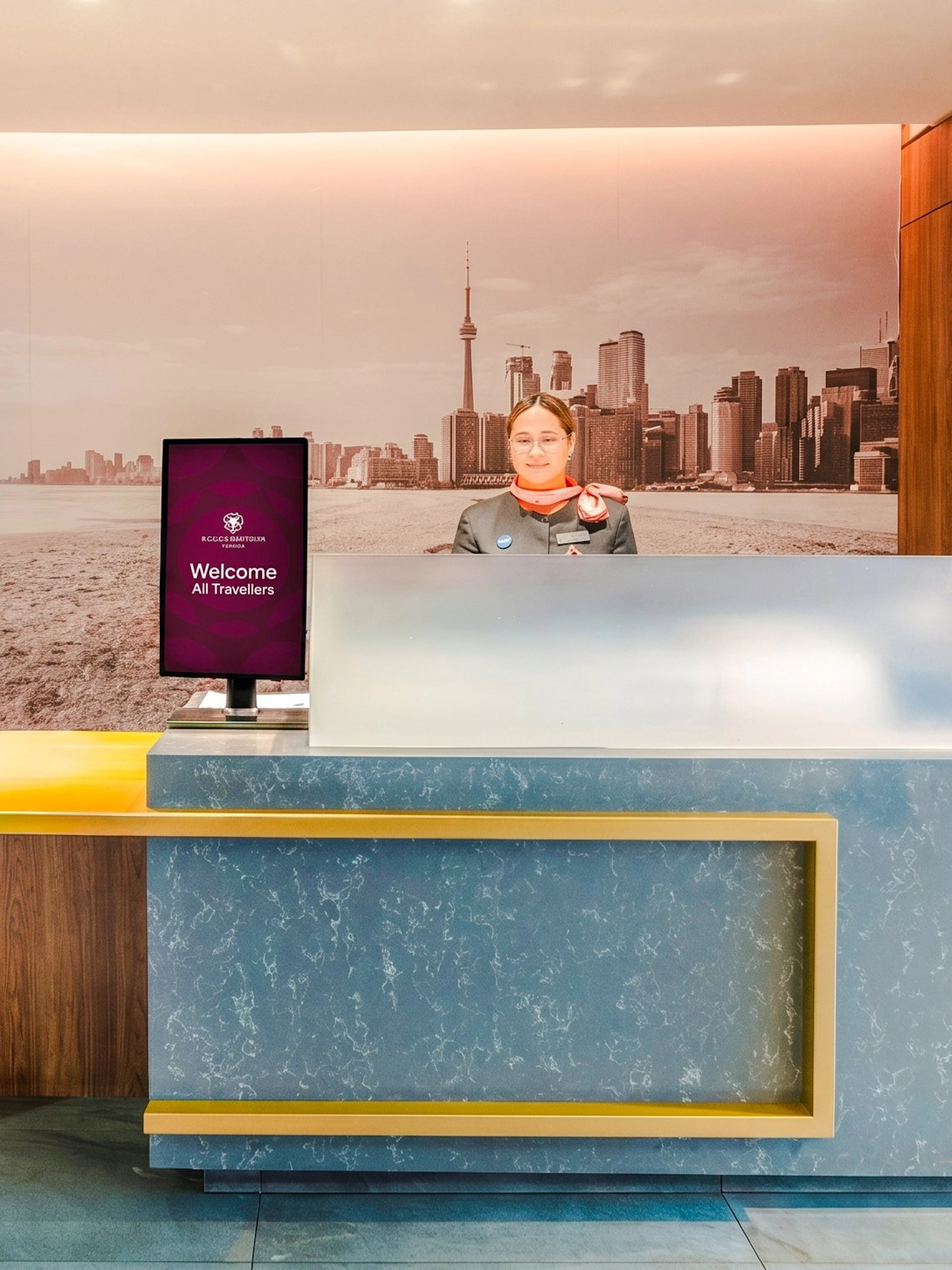 Reception desk at Plaza Premium Lounge, Terminal 3, Toronto Pearson Airport with city skyline mural.