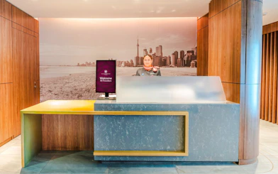Reception desk at Plaza Premium Lounge, Terminal 3, Toronto Pearson Airport with city skyline mural.