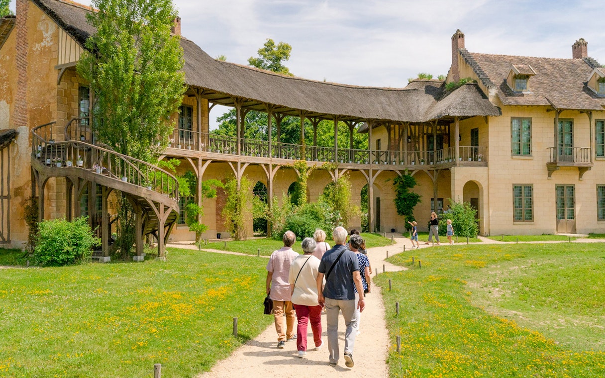 Visitors walking towards the Domain of Marie Antoinette, Palace of Versailles.