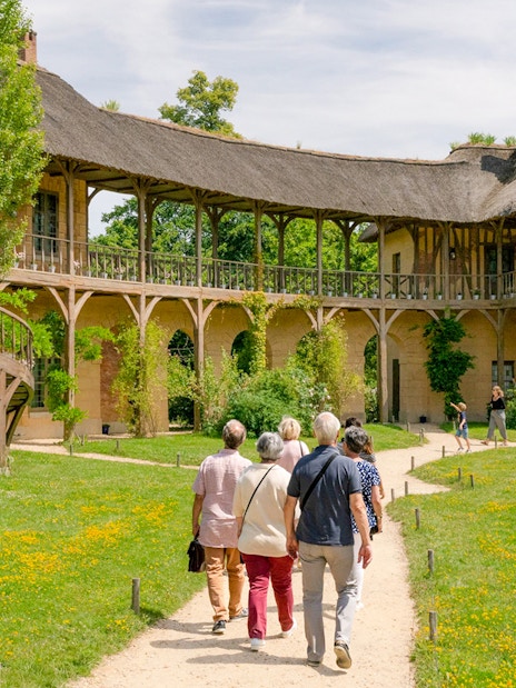 Visitors walking towards the Domain of Marie Antoinette, Palace of Versailles.