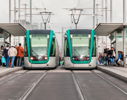 Tourists boarding trams at a Barcelona station with cityscape views.