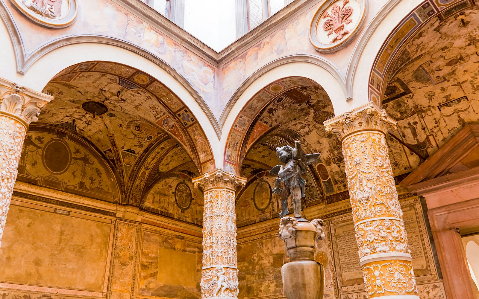 Palazzo Vecchio courtyard with ornate columns and detailed frescoes in Florence, Italy.