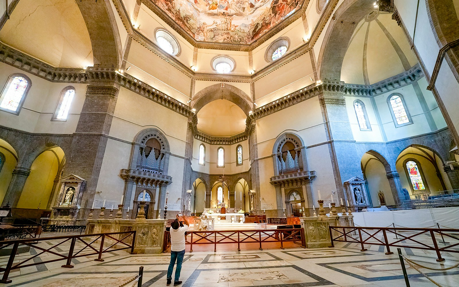 Florence Cathedral interior with visitor taking photos of ornate ceiling.