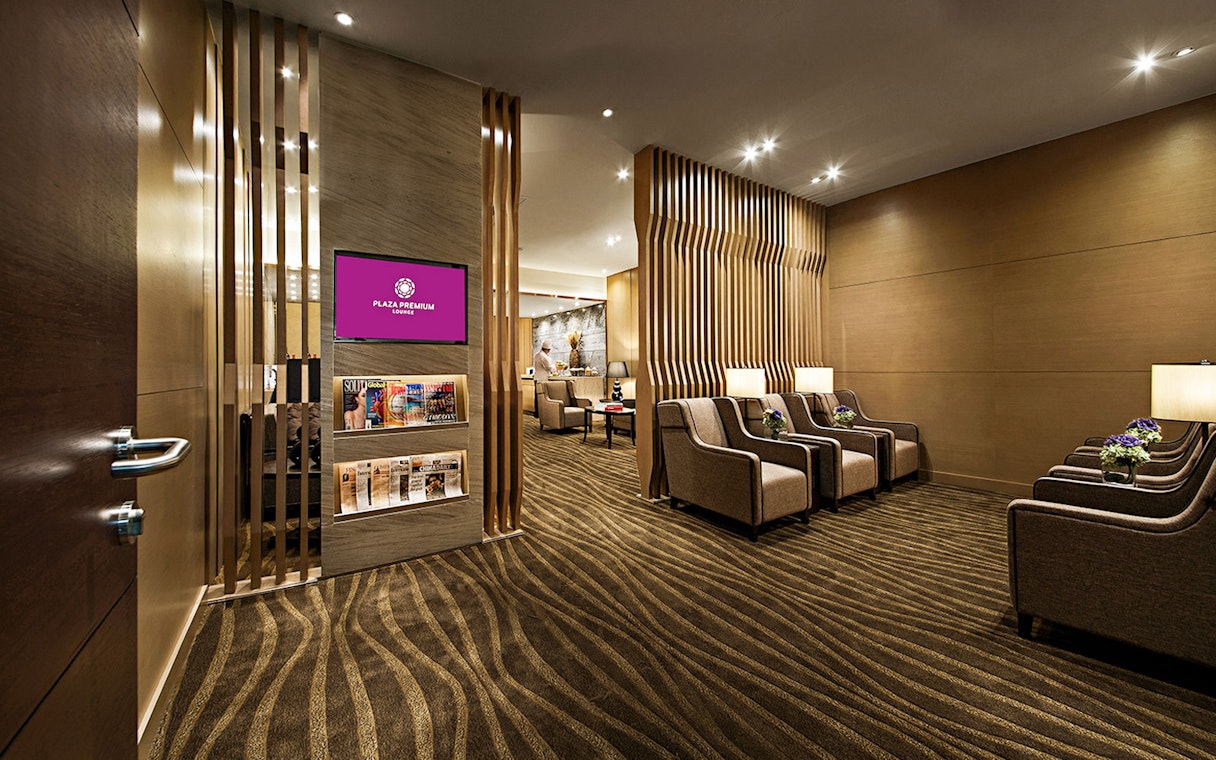 Plaza Premium Lounge seating area with armchairs and magazines.