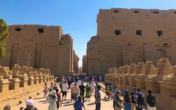 Visitors walking through the avenue of sphinxes at Karnak Temple, Egypt.