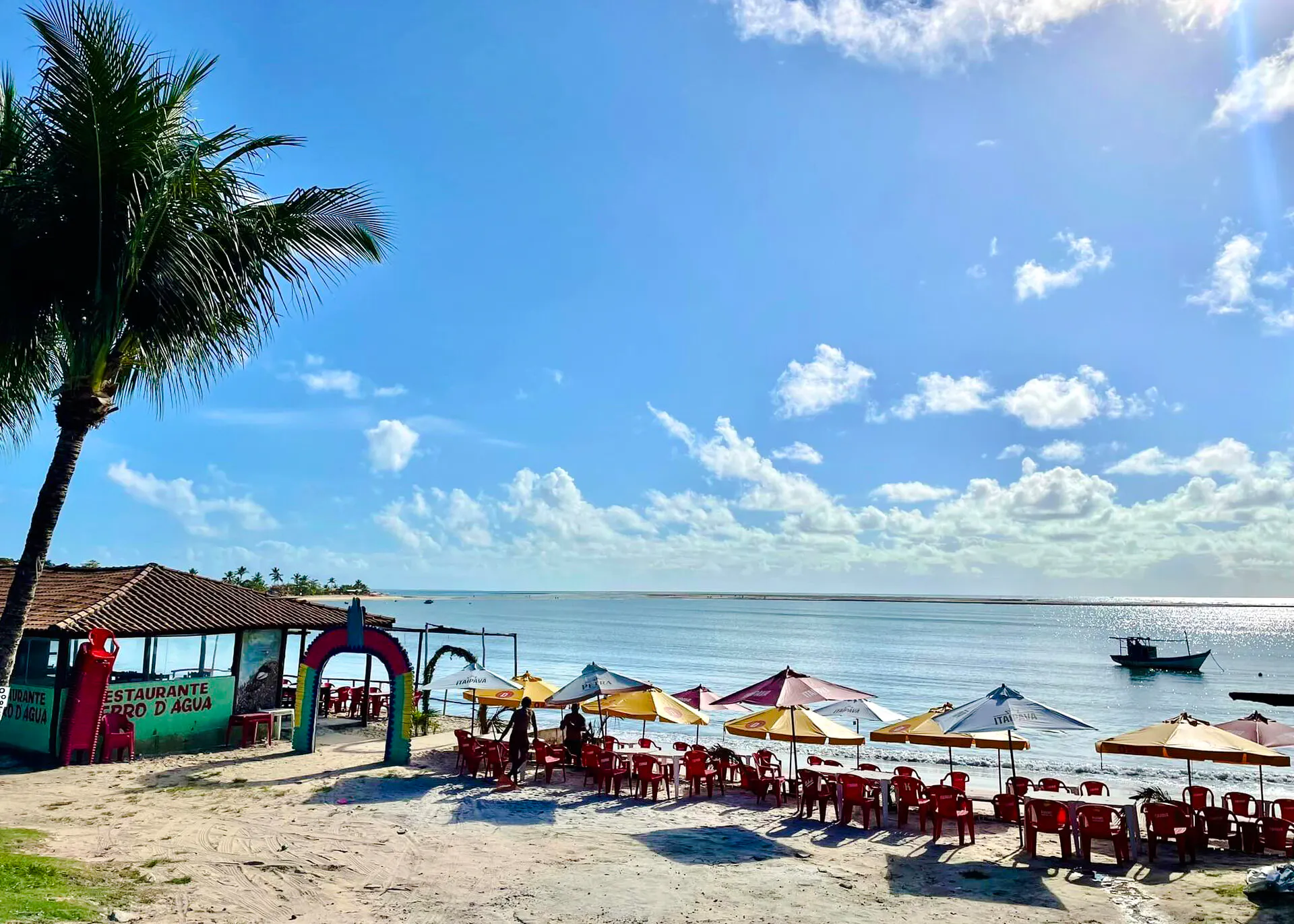 Beachfront restaurant with colorful umbrellas and chairs in Coroa Vermelha, Porto Seguro, Brazil.