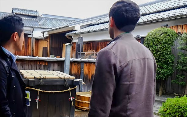 Visitors observing traditional sake barrels at a Kyoto brewery during a sake tour.
