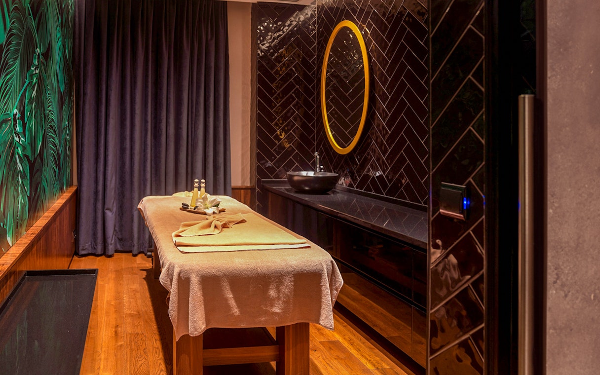 Massage table in a private Turkish bath with dark tiles and a round mirror in Istanbul spa.