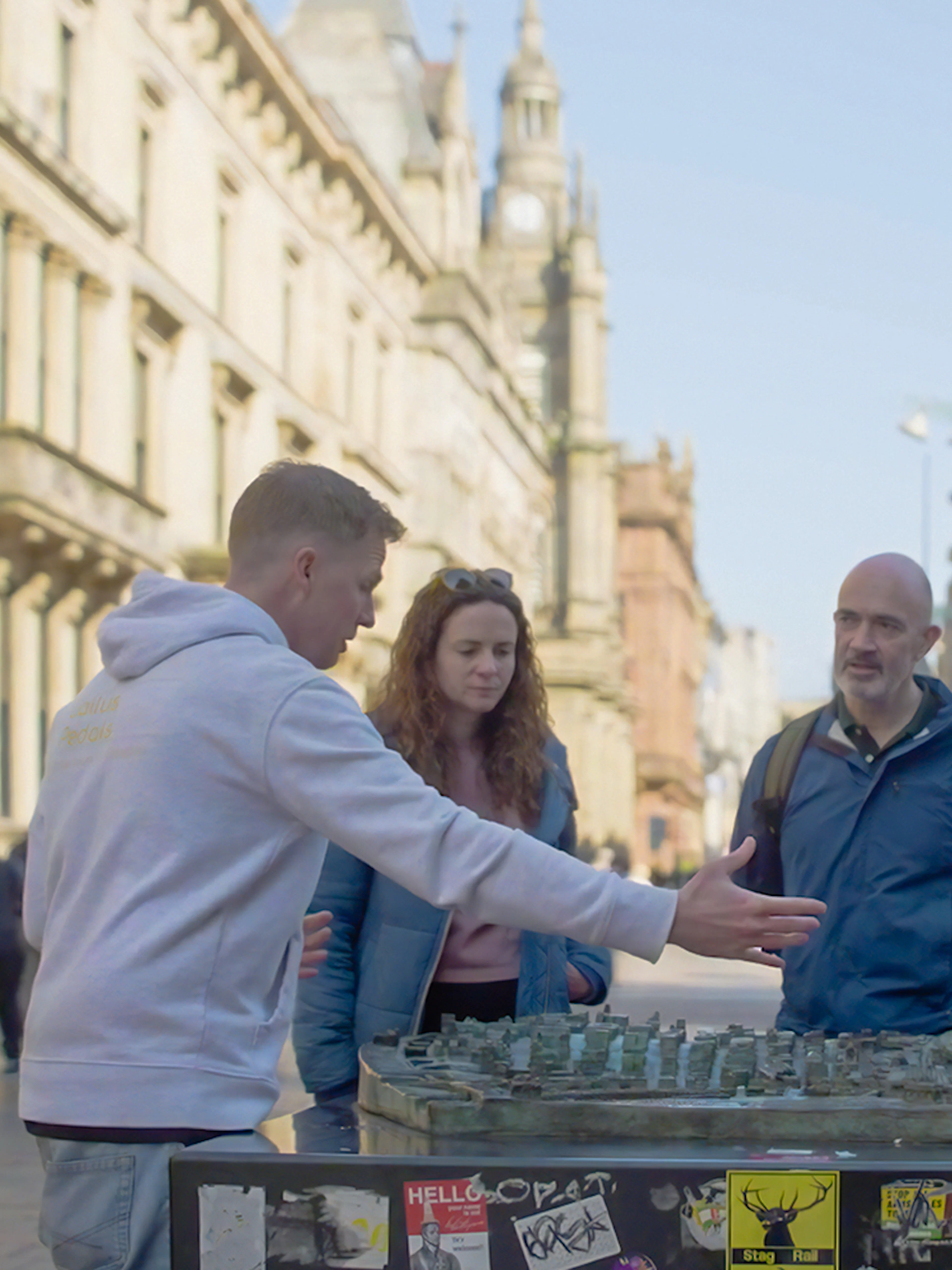 Tour guide explaining a city model to a group during a walking tour in Glasgow.