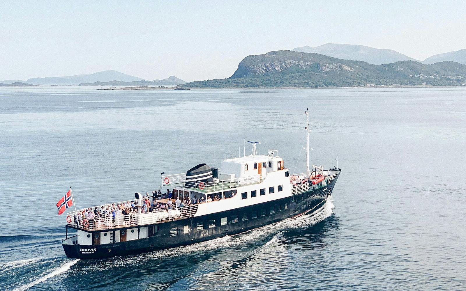 Fjord boat cruising near Ålesund with passengers on deck.