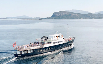Fjord boat cruising near Ålesund with passengers on deck.